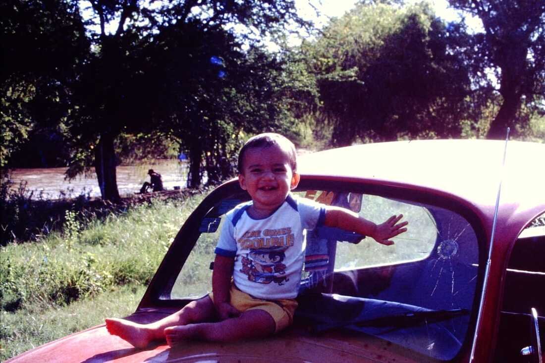 David sitting on the hood of his father's Volkswagen Beetle in the 1980s