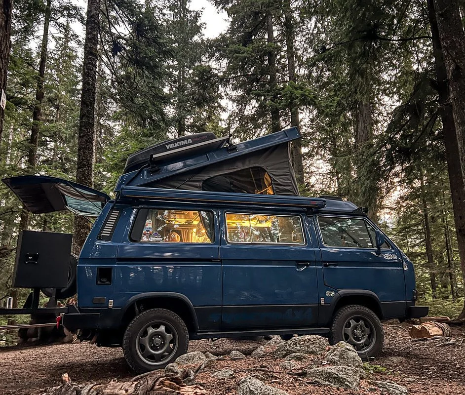 Miki, now blue, with the pop-top raised in a forest campsite near Whistler