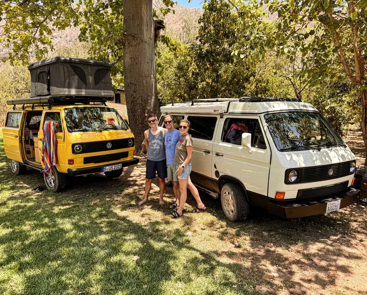 Two people between yellow and white Volkswagen camper vans
