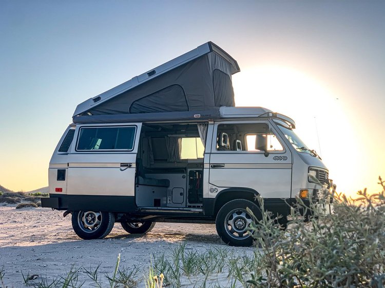 Volkswagen Westfalia parked at the beach with its pop-top raised