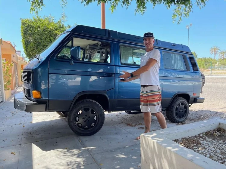 Person beside a blue Volkswagen Vanagon
