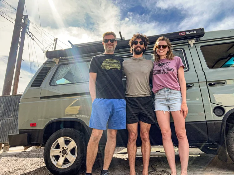 Three people beside a gray Volkswagen camper