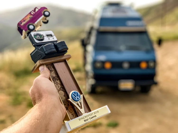 Volkswagen-themed trophy held in front of a blue camper van
