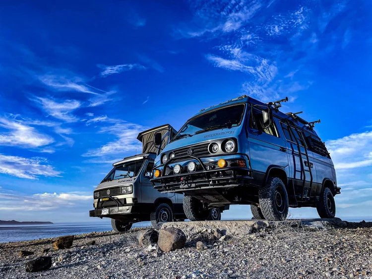 Blue Volkswagen camper with off-road accessories on rocky ground