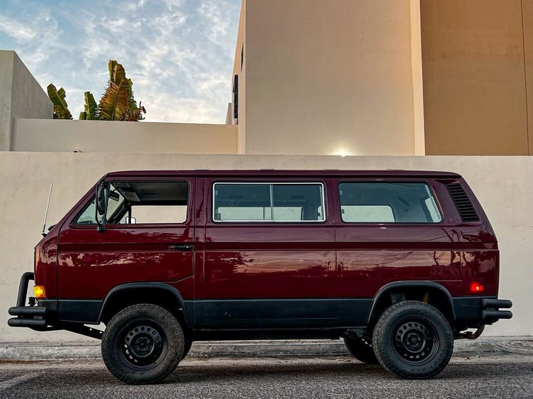 Burgundy Volkswagen Vanagon with black wheels in profile