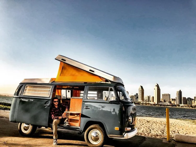 Dark Volkswagen Bus with open sliding door and raised pop-top