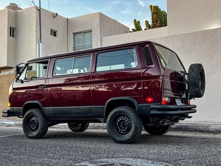 Rear three-quarter view of a burgundy Volkswagen Vanagon with spare wheel