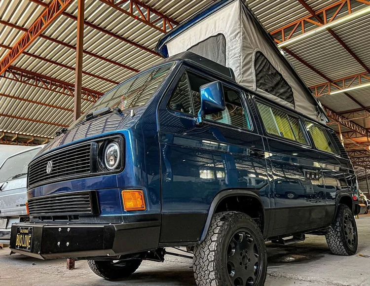Dark blue Volkswagen camper with raised pop-top inside the workshop