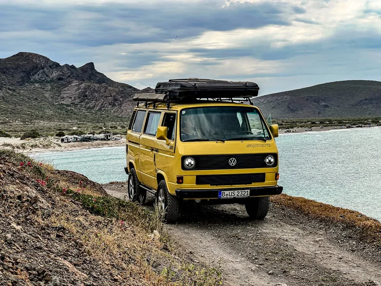 Yellow Volkswagen camper on a rocky coastal track