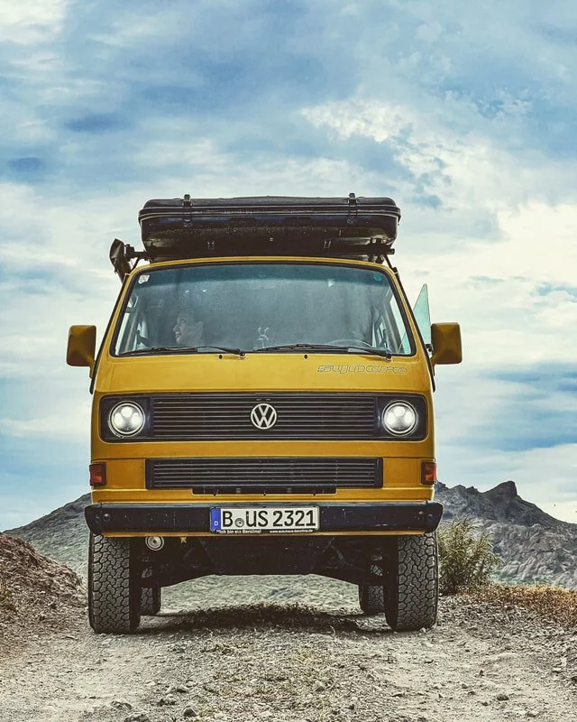 Front view of a yellow Volkswagen camper with roof-mounted equipment