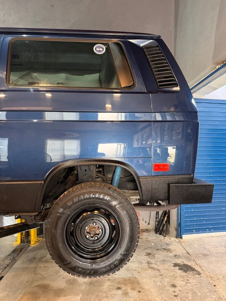 Rear quarter of a blue Volkswagen Vanagon on a workshop lift