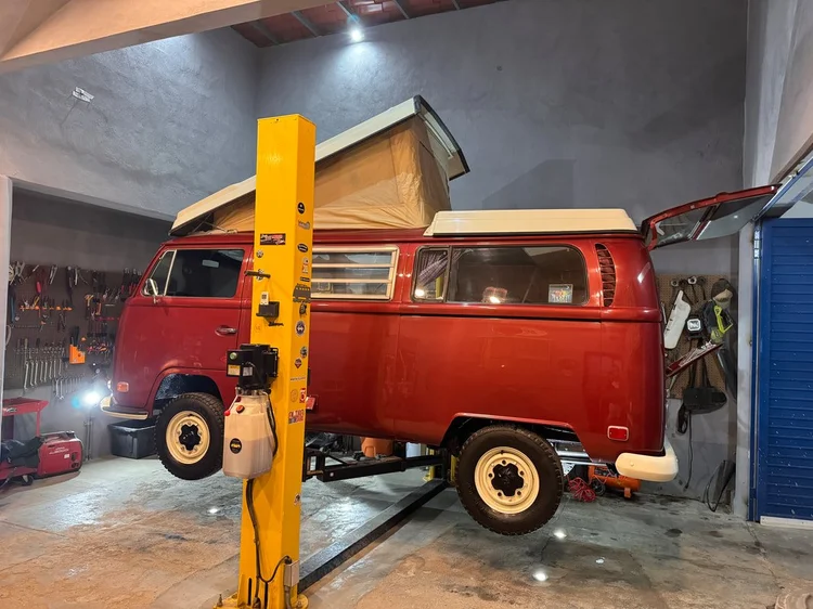 Red Volkswagen Westfalia with raised pop-top on a lift