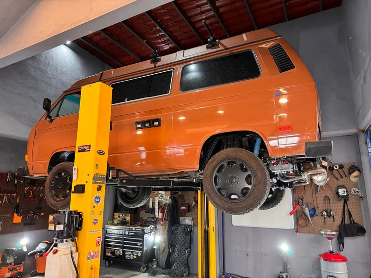 Orange Volkswagen Vanagon raised on the workshop lift
