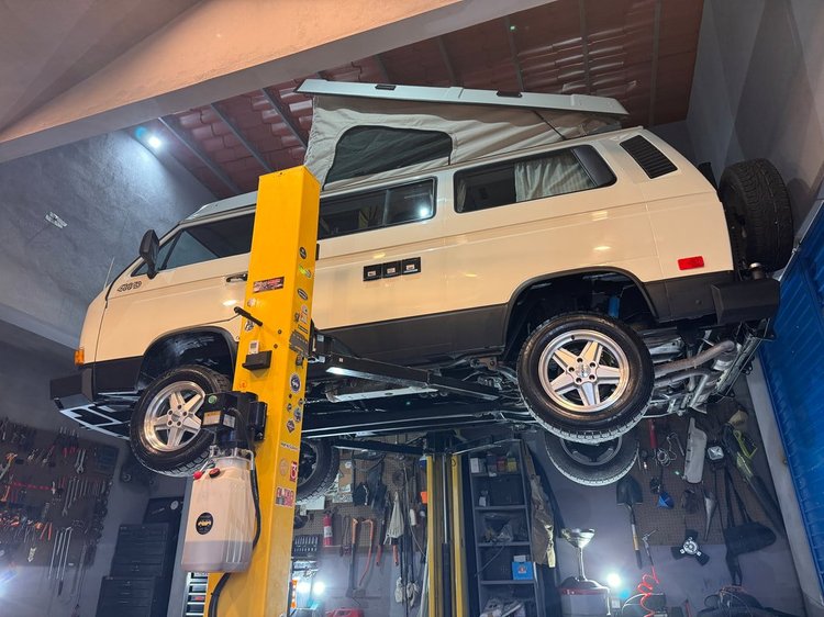 Cream Volkswagen Vanagon raised on a workshop lift