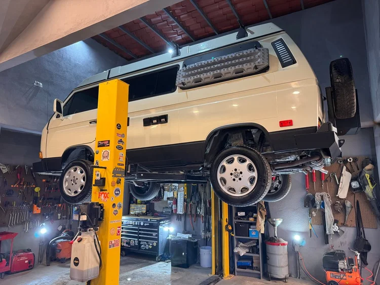 Cream Volkswagen Vanagon with an exterior storage panel on a lift