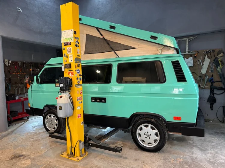 Mint green Volkswagen Westfalia with raised pop-top inside the workshop