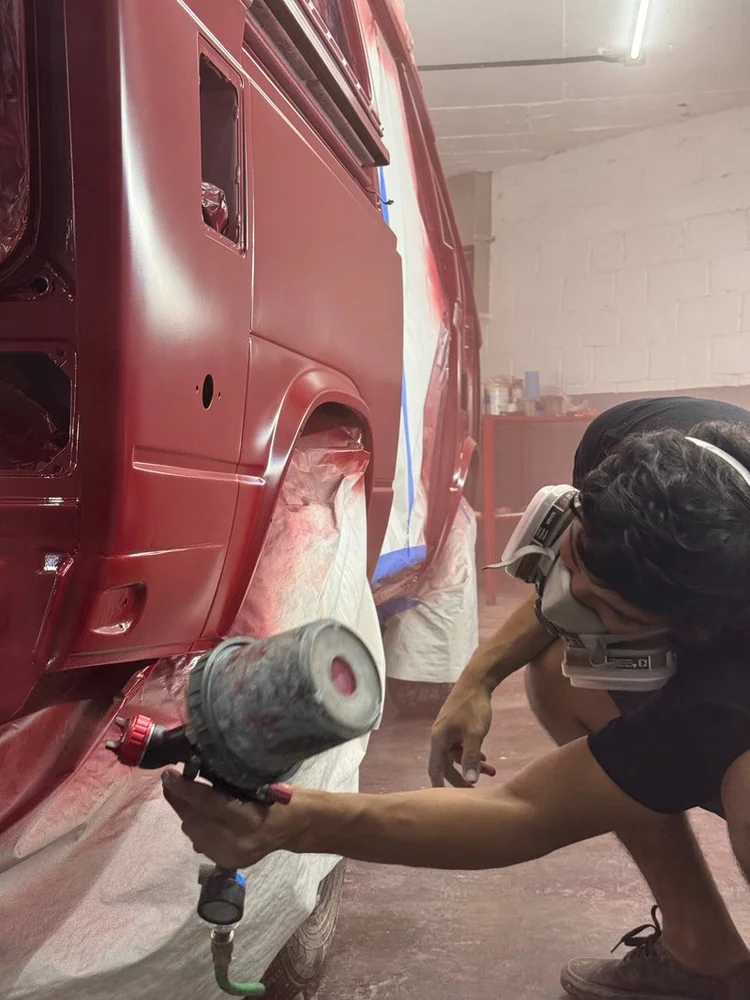 Technician polishing the rear corner of a red Volkswagen van