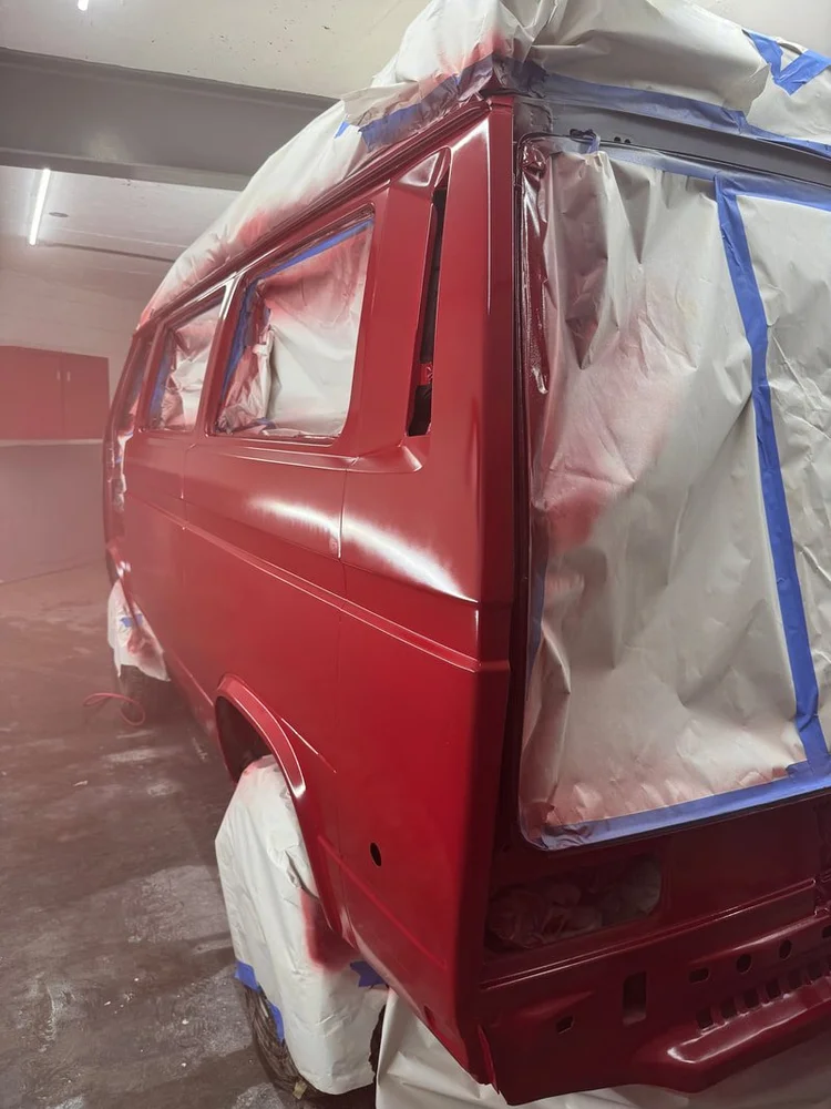 Red Volkswagen van with masked windows in the paint booth
