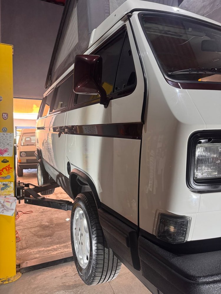 White Volkswagen camper front quarter beside a workshop lift