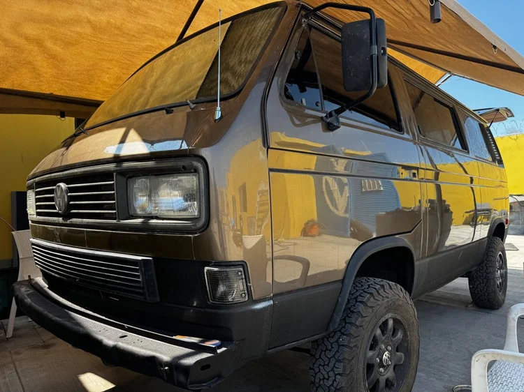 Brown Volkswagen camper under a shade canopy