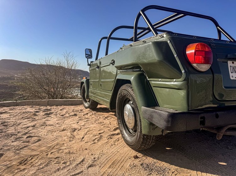 Rear quarter of a green Volkswagen Thing on a dirt track