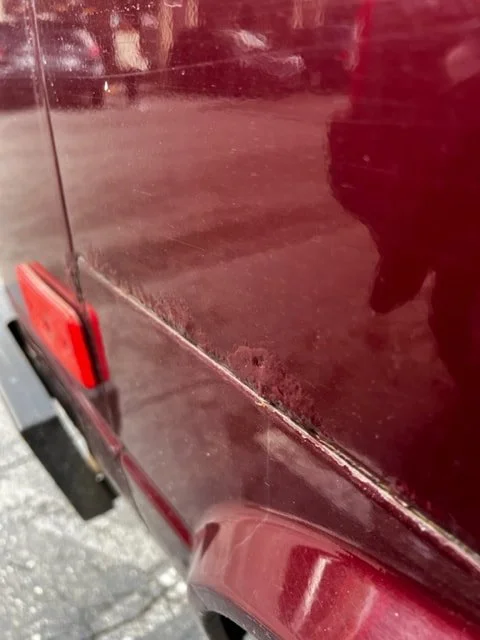 Close-up of marks along a burgundy Volkswagen side panel