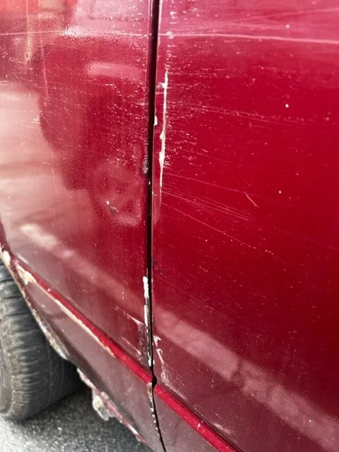 Close-up of scratches beside a burgundy Volkswagen door seam