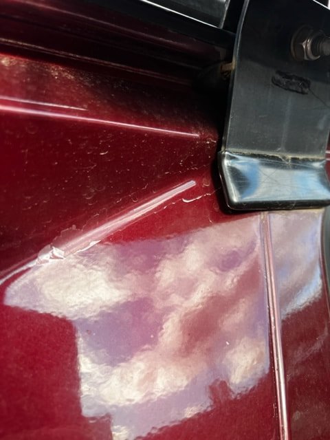 Close-up of a burgundy Volkswagen mirror mount and bodywork