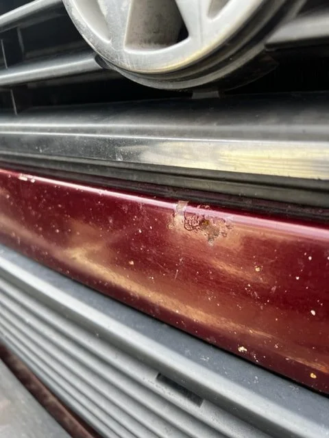 Close-up of a Volkswagen badge, grille and burgundy front panel