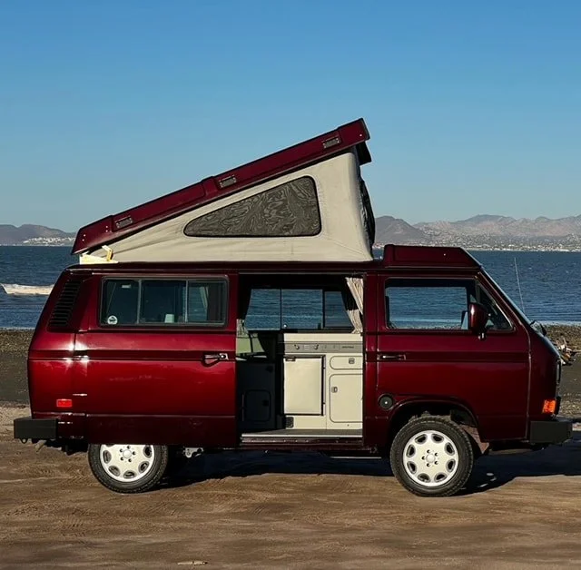 Burgundy Volkswagen Westfalia with raised pop-top and open sliding door