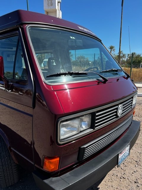 Front quarter of a burgundy Volkswagen Westfalia in sunlight
