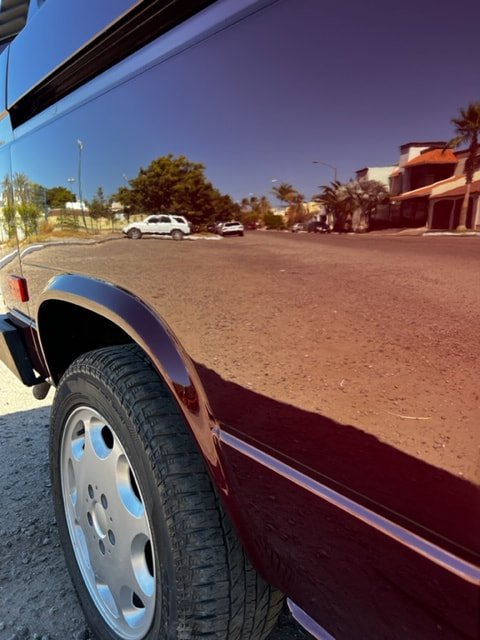 Close-up of reflections in a burgundy Volkswagen side panel
