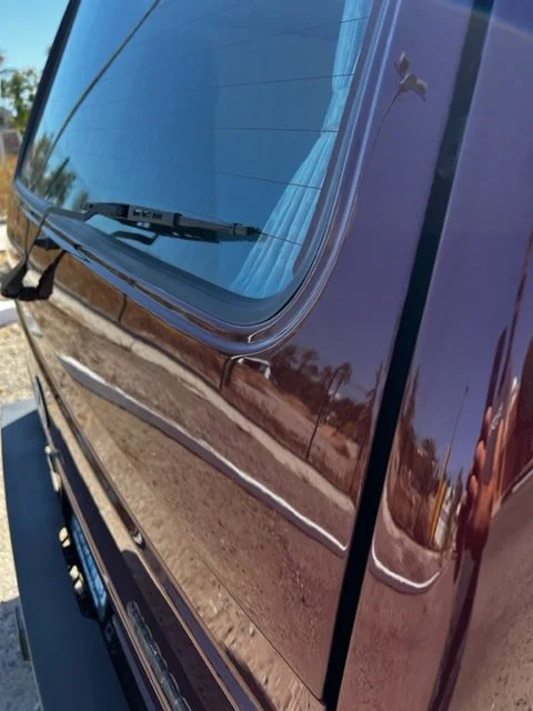 Close-up of a burgundy Volkswagen rear window and body panel