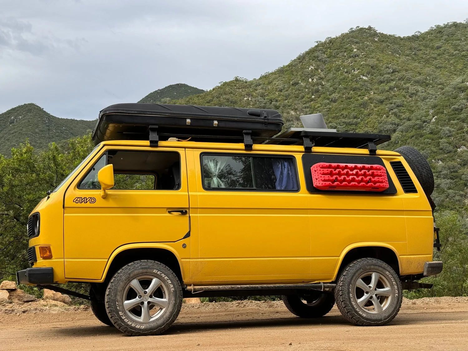 Yellow Vanagon Syncro equipped with a roof rack, awning, spare wheel and recovery boards, from LiveTheVanLife's upgrade gallery