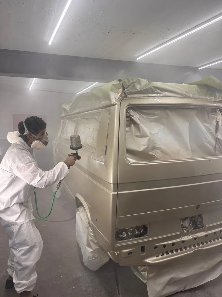 Painter working on the side of a masked Volkswagen van