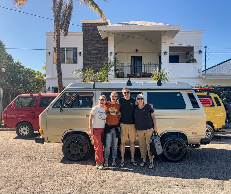 Four people beside a cream Volkswagen camper outside the workshop
