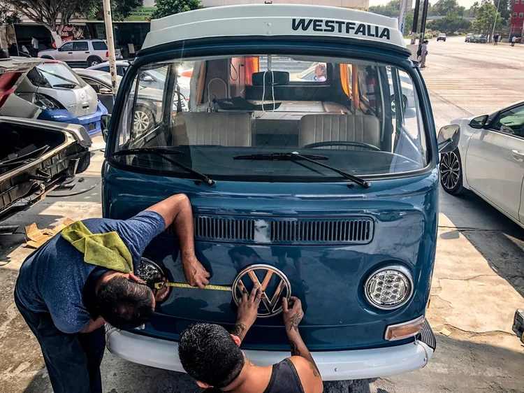 Person working at the front of a blue-and-white Volkswagen Westfalia