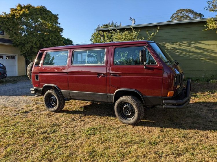 Side view of a burgundy Volkswagen van parked on grass