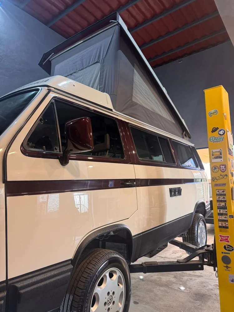 Front quarter of a white Volkswagen camper with raised pop-top
