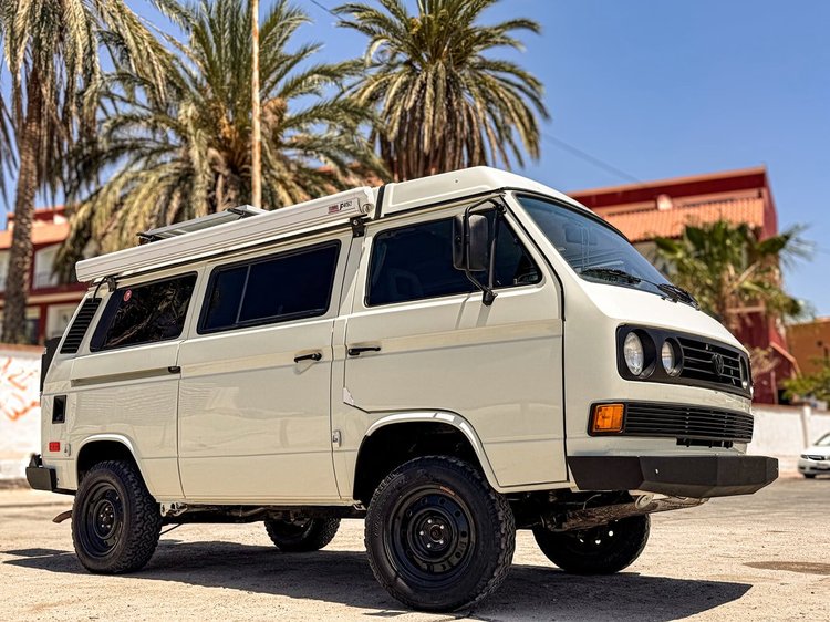 Cream Volkswagen Vanagon parked outside under palm trees