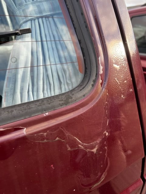 Close-up of a Volkswagen side window and surrounding burgundy bodywork