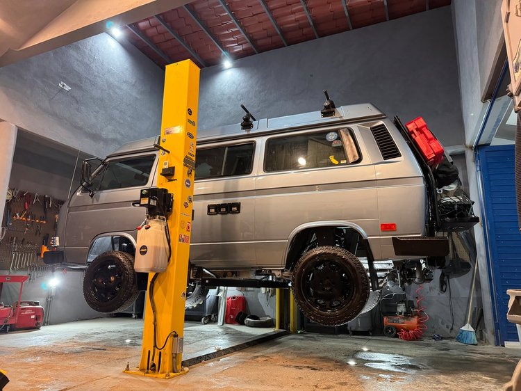 Silver Volkswagen Vanagon with a rear ladder on a lift