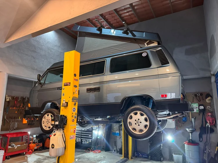 Silver Volkswagen Vanagon with raised pop-top on a workshop lift