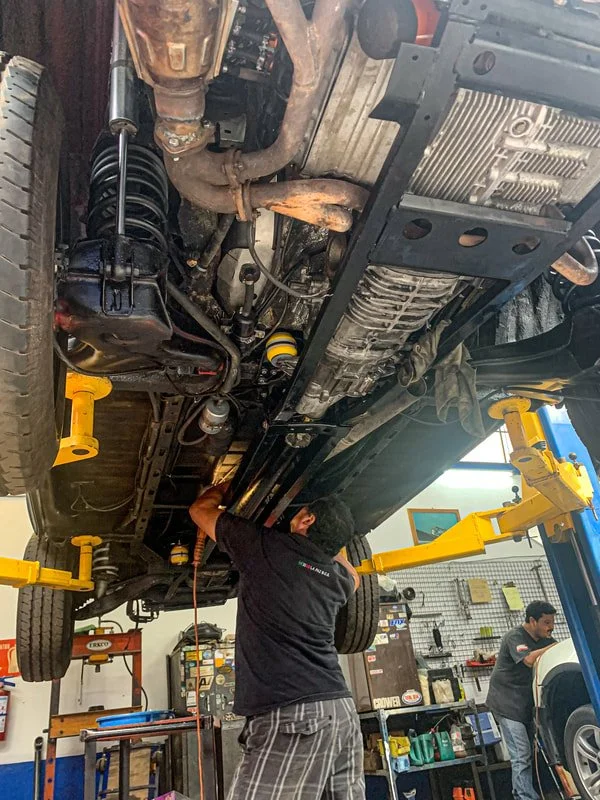 A mechanic working beneath a Vanagon on a workshop lift