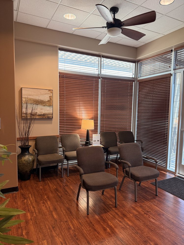 The Van Metre Chiropractic waiting room with cushioned chairs, wood flooring and warm lighting.