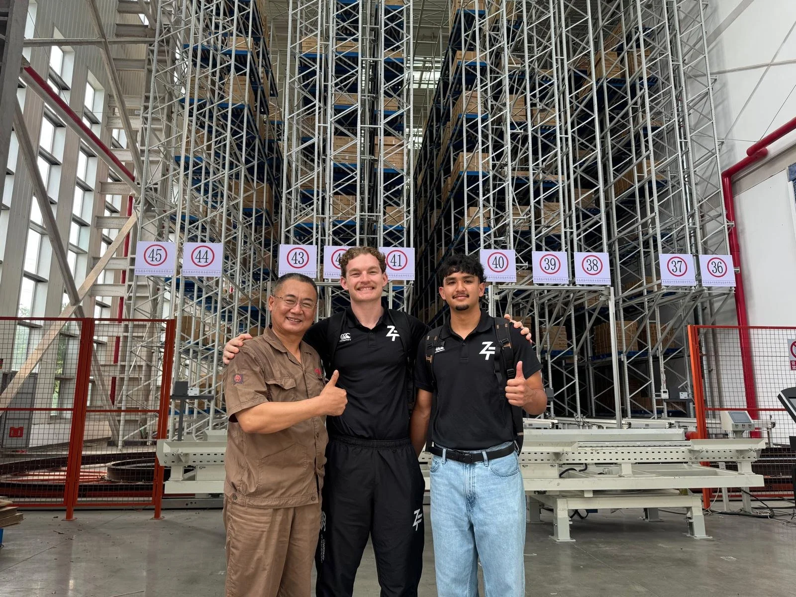 Three people standing together during a visit to an equipment manufacturing facility