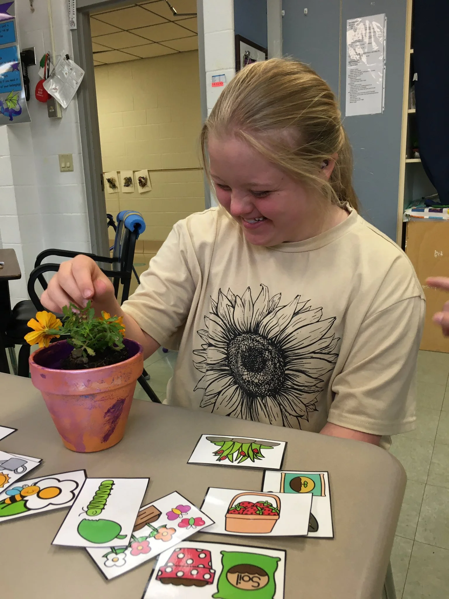 A young adult program participant carefully tending to a flower in a painted pot — engaged in a purposeful, skill-building activity.