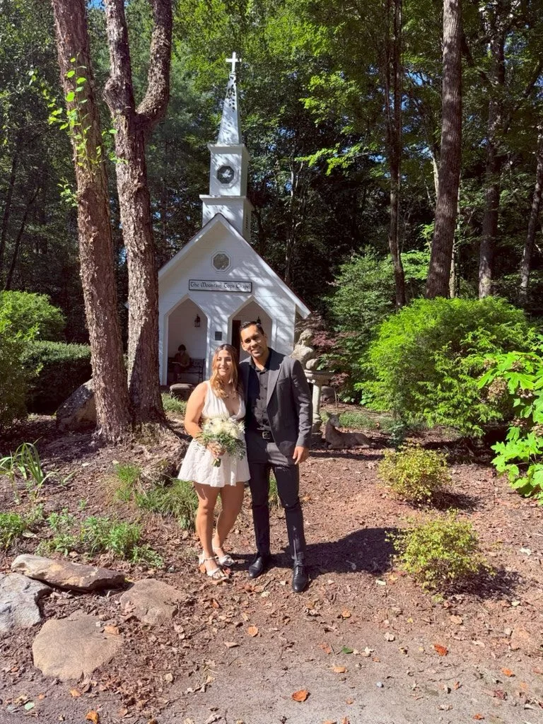 Luna and Alexander posing outside a small mountain chapel after their Blue Ridge, Georgia wedding ceremony with officiant Emilie Gates