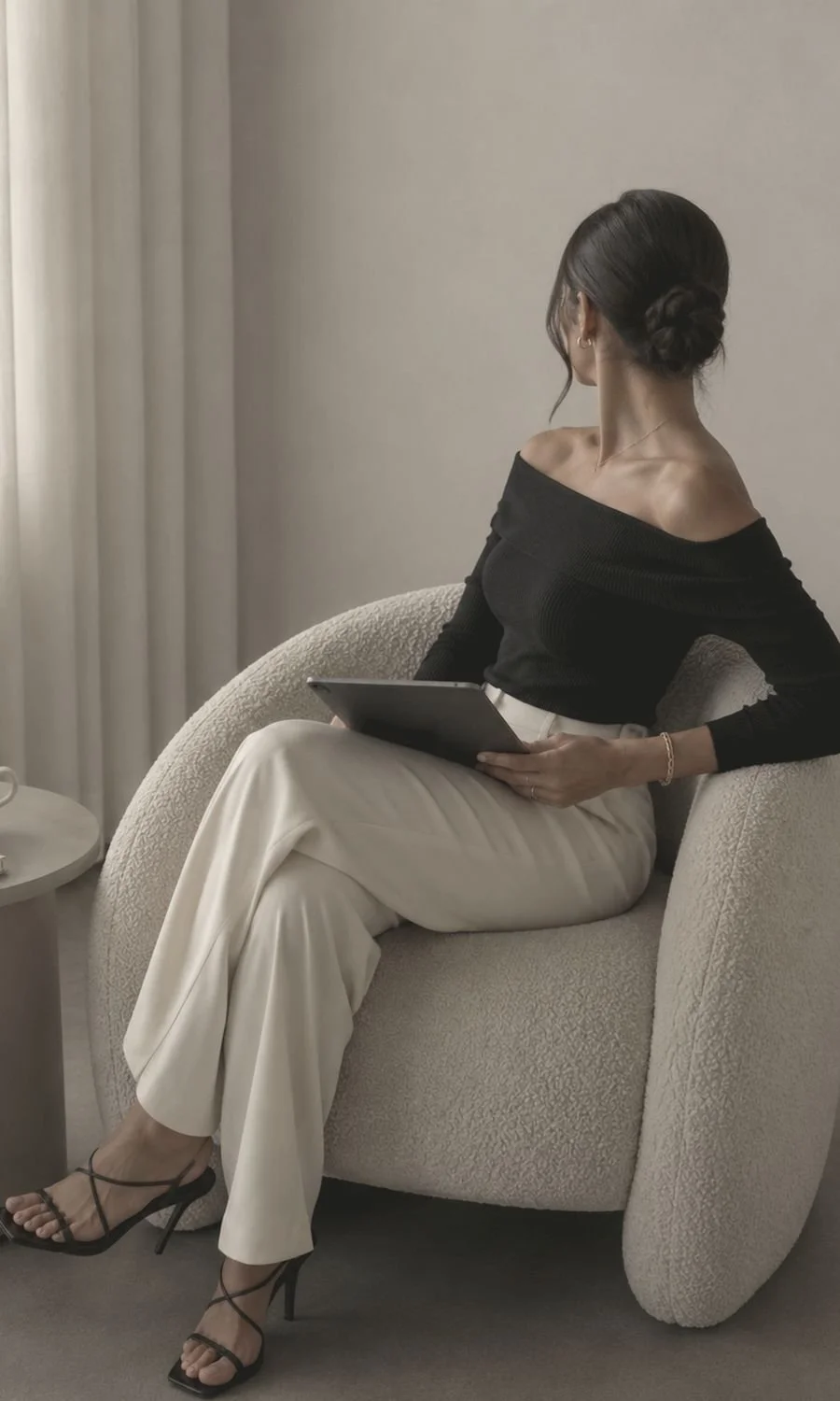 A woman seated in a chair with a tablet held like a notebook