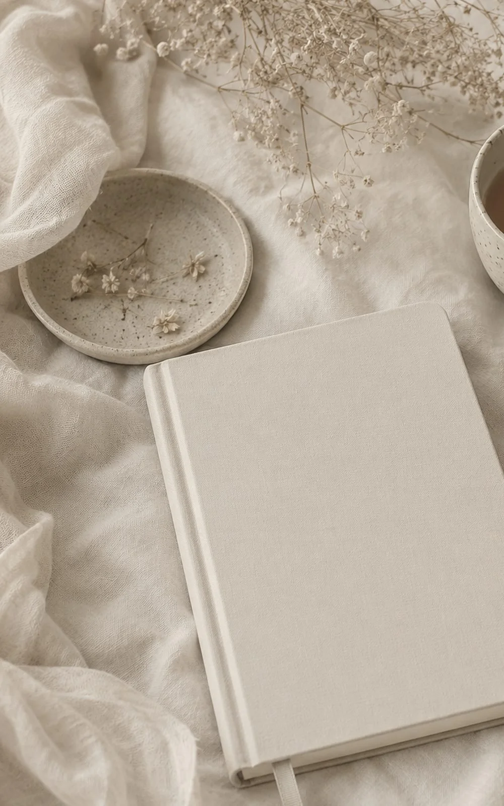 A cloth-bound notebook on linen with dried flowers